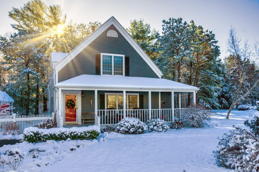 A house sits with snow all around it. 